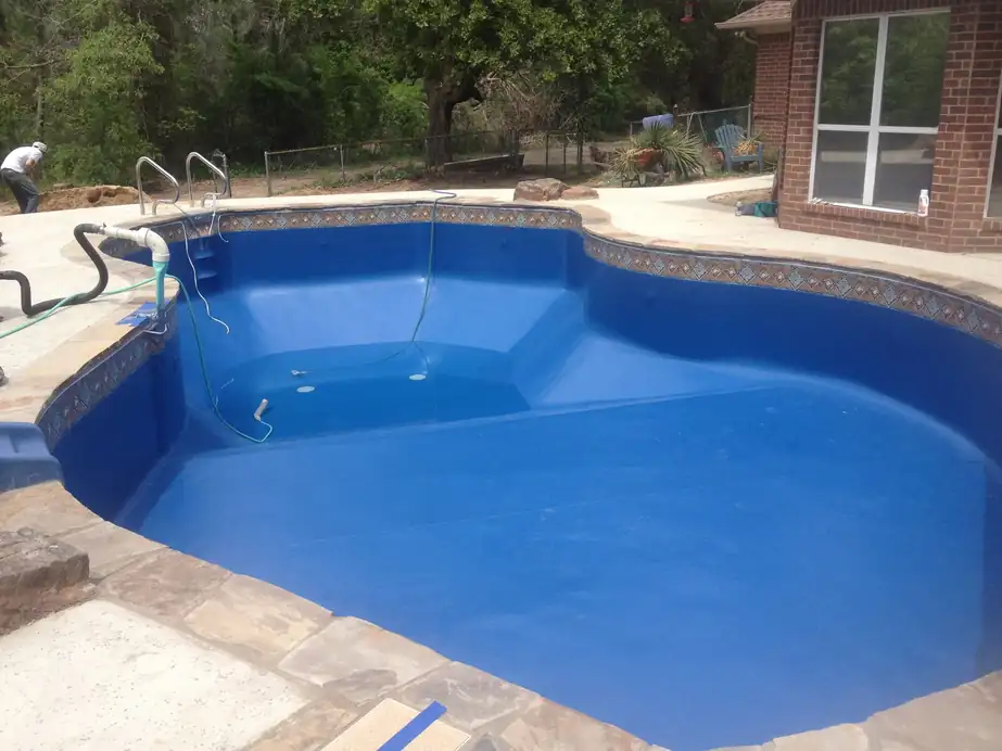 A freshly fitted royal-blue liner filling inside flagstone coping, hose in the deep end