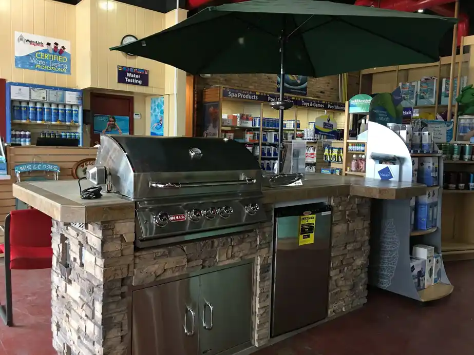 A Bull outdoor kitchen island under an umbrella inside the store