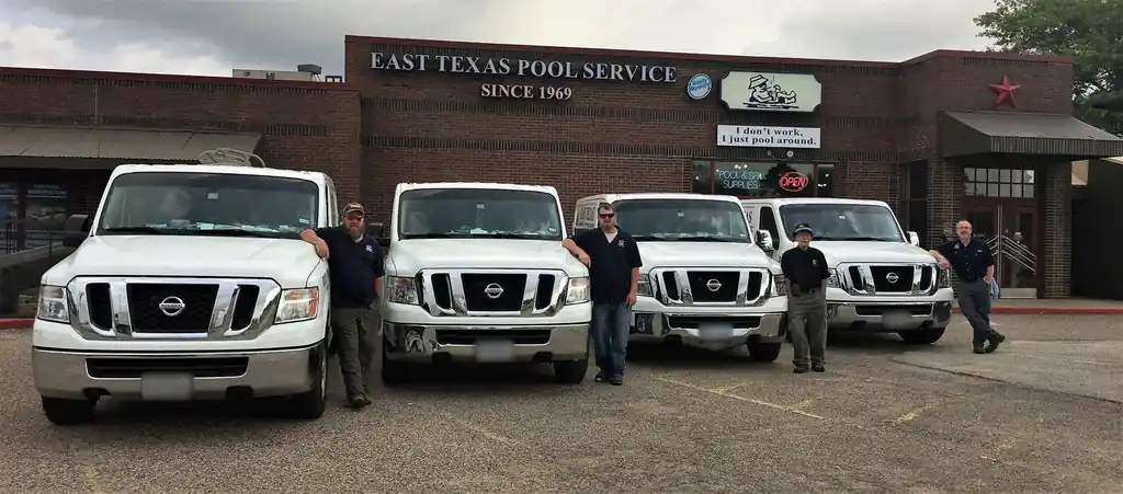 Four crew members beside four white service vans outside the store